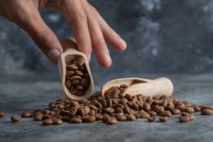Hand holding a wooden spoon with coffee beans. High quality photo